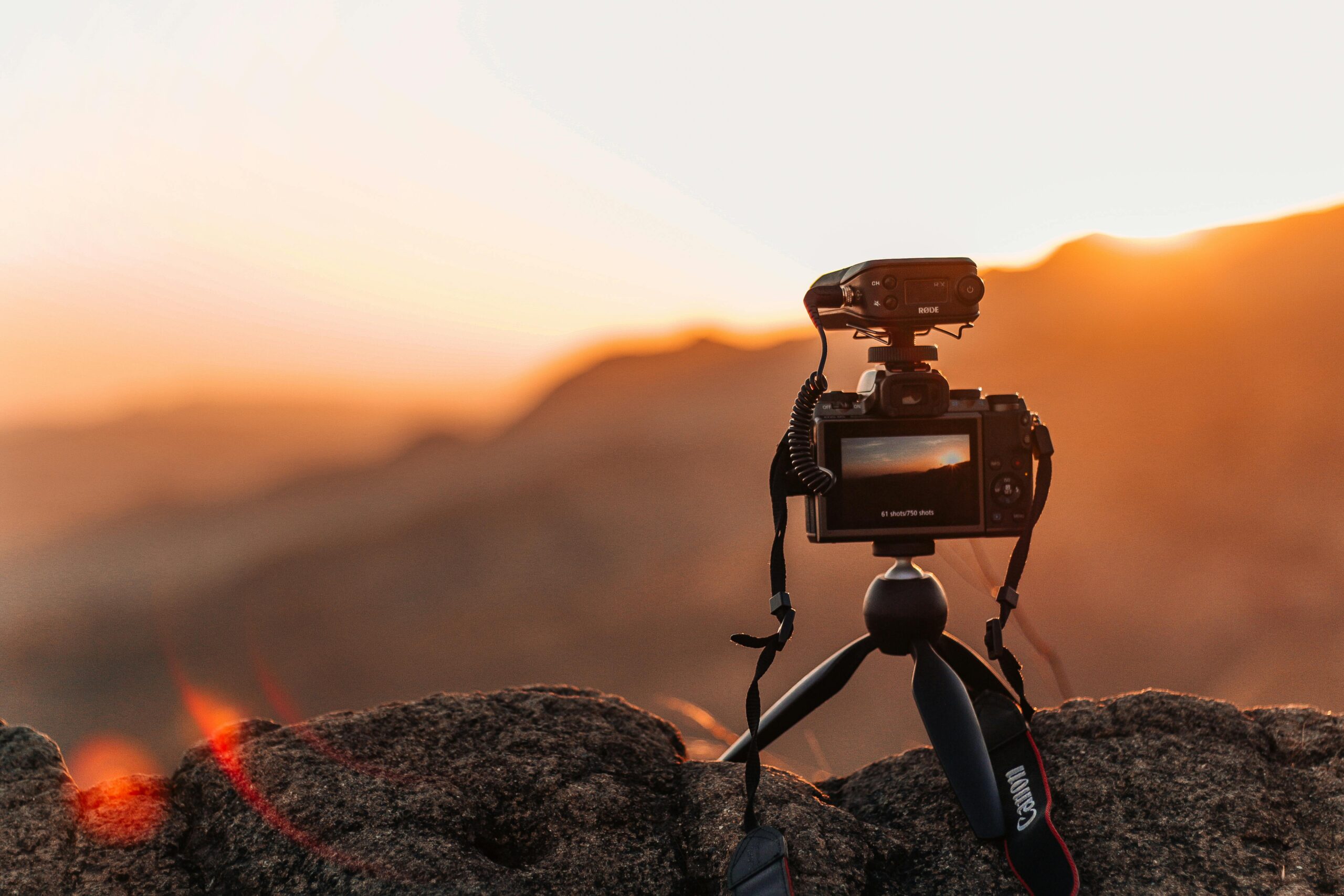 A DSLR camera on a tripod capturing a picturesque sunset over rocky mountains in Panama.